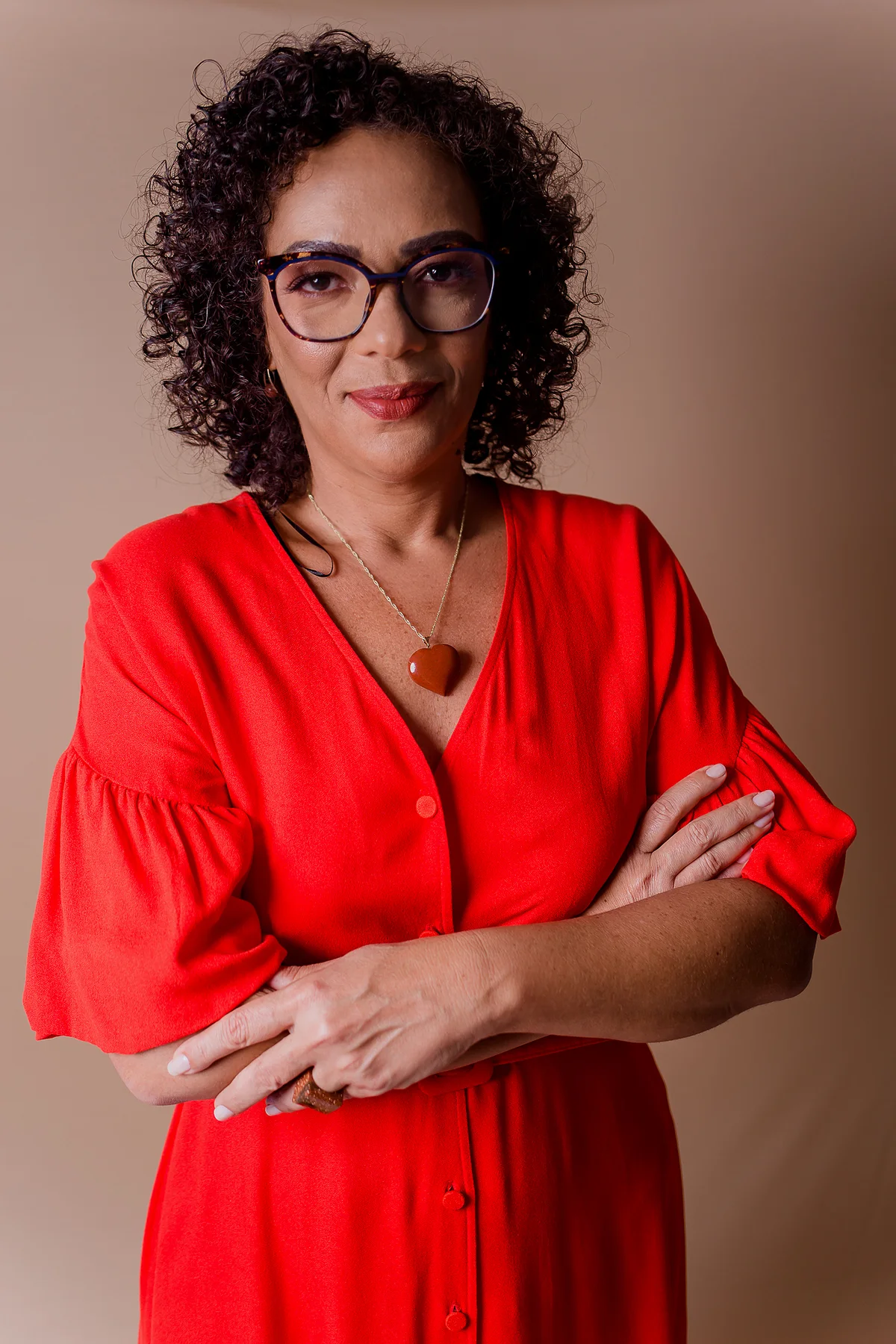 Dra. Ana Paula Teixeira, médica do trabalho, de vestido vermelho e braços cruzados